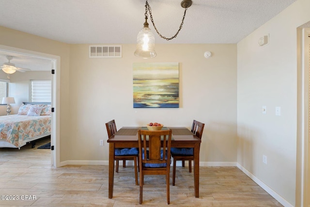 dining area featuring visible vents, a textured ceiling, baseboards, and wood finished floors