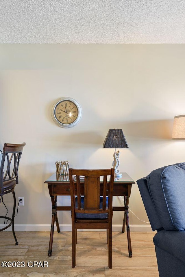 dining area with light wood-style flooring, baseboards, and a textured ceiling