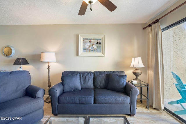 living room with a textured ceiling, a ceiling fan, and wood finished floors