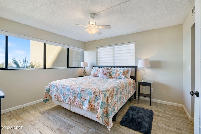 bedroom featuring a textured ceiling, wood finished floors, a ceiling fan, and baseboards