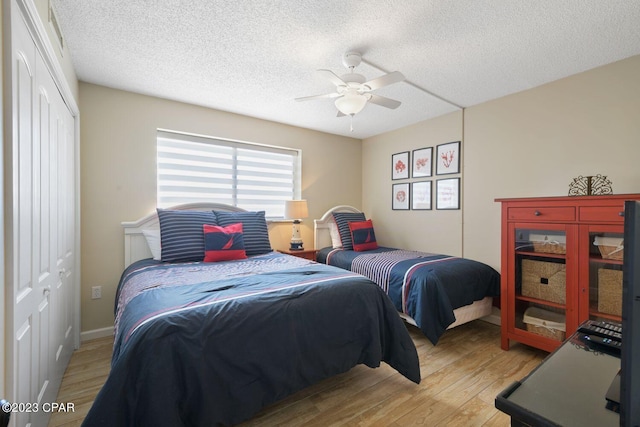 bedroom featuring a textured ceiling, ceiling fan, a closet, and light wood-style flooring