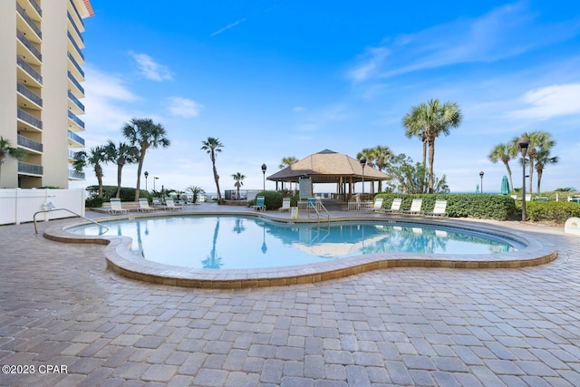 community pool with a gazebo, a patio, and fence