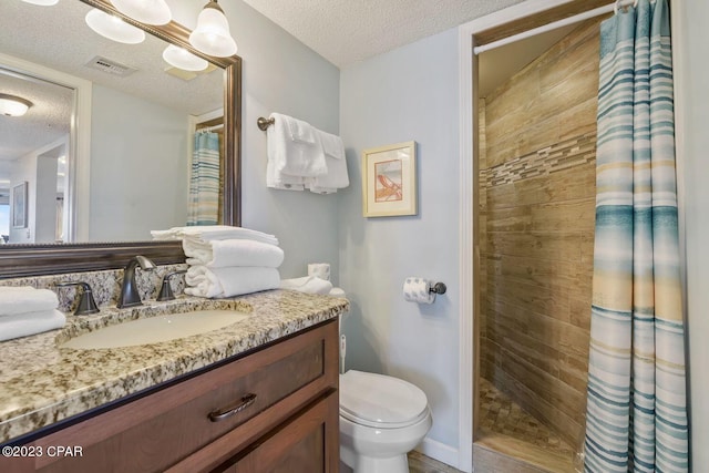 bathroom featuring visible vents, a tile shower, a textured ceiling, and vanity