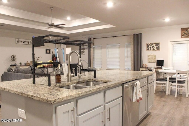 kitchen with stainless steel dishwasher, sink, ornamental molding, and an island with sink