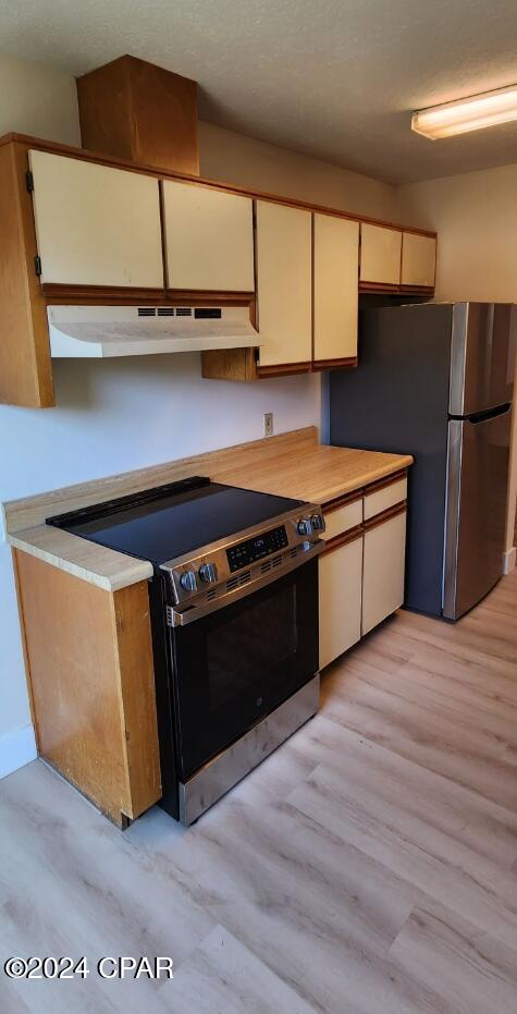 kitchen with stove, stainless steel fridge, and light hardwood / wood-style floors