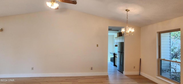 empty room with light hardwood / wood-style flooring, a textured ceiling, vaulted ceiling, and an inviting chandelier