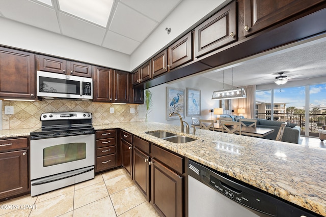 kitchen featuring tasteful backsplash, appliances with stainless steel finishes, dark brown cabinets, light tile patterned floors, and sink