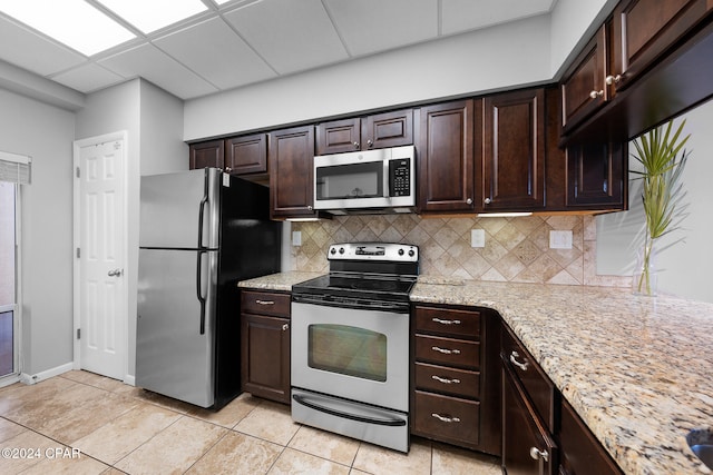 kitchen featuring dark brown cabinetry, appliances with stainless steel finishes, a drop ceiling, light tile patterned floors, and decorative backsplash