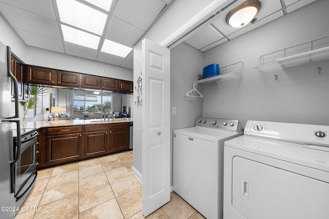 clothes washing area with light tile patterned flooring, washer and dryer, and sink