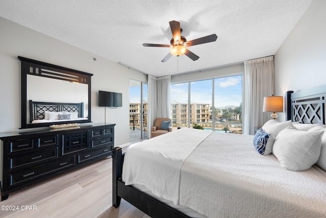 bedroom with ceiling fan, access to exterior, a textured ceiling, and light hardwood / wood-style flooring