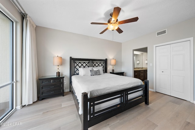 bedroom with a closet, light hardwood / wood-style floors, ceiling fan, and ensuite bathroom