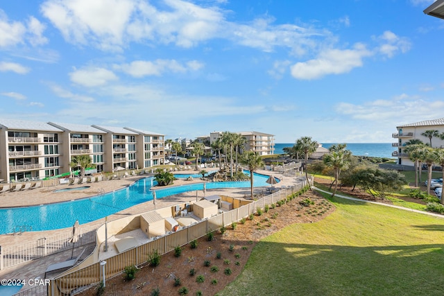 view of swimming pool with a patio area, a water view, and a lawn