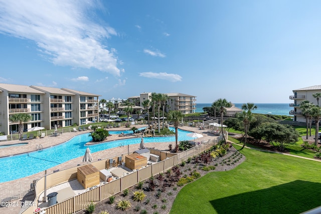 view of pool with a patio area, a water view, and a yard