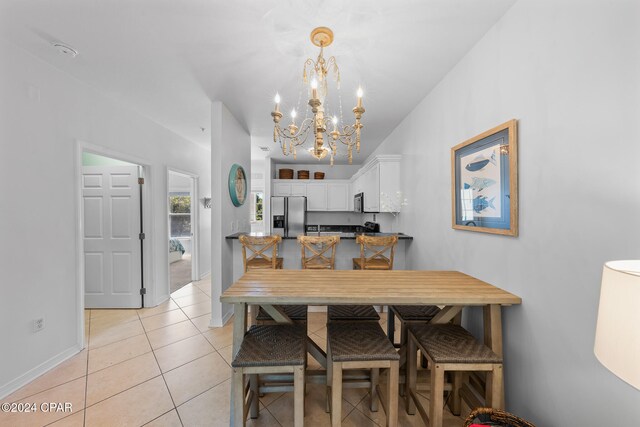 tiled dining room with a chandelier and lofted ceiling