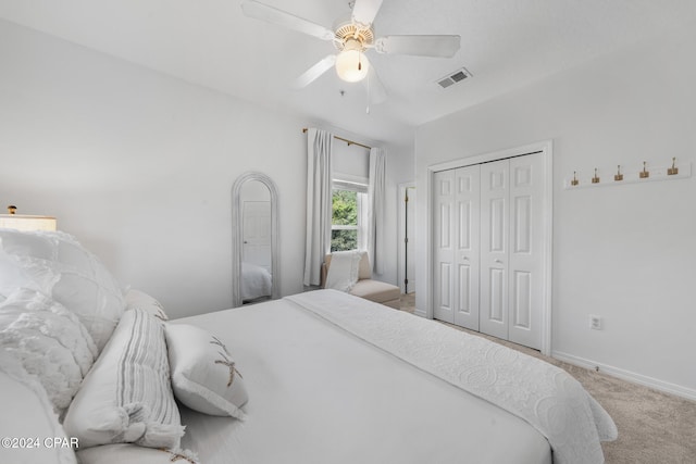 bedroom with light colored carpet, ceiling fan, and a closet