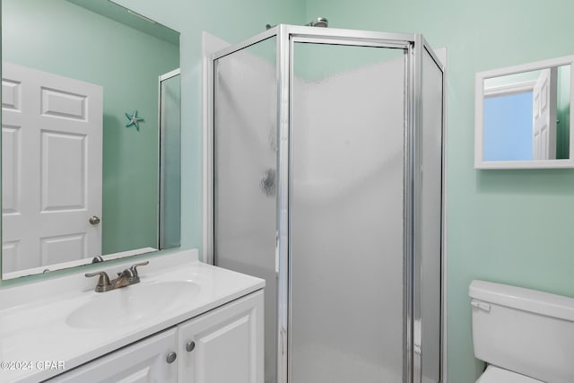 bathroom featuring toilet, vanity, and a shower with door