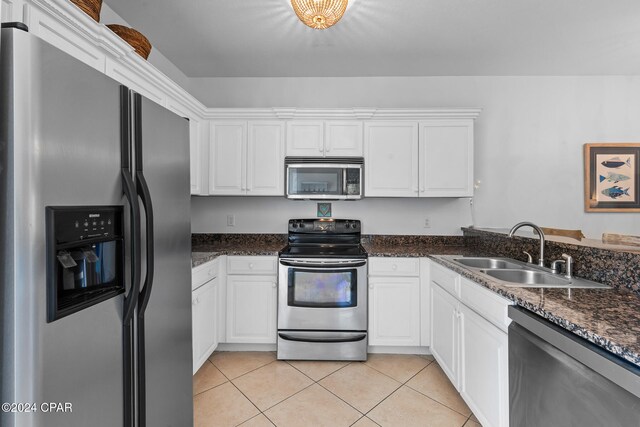 kitchen with appliances with stainless steel finishes, sink, light tile patterned floors, and white cabinets