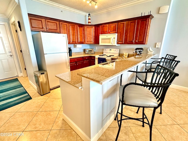 kitchen featuring a kitchen breakfast bar, kitchen peninsula, a textured ceiling, and white appliances