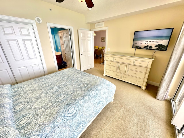 carpeted bedroom featuring a closet, ensuite bathroom, and ceiling fan