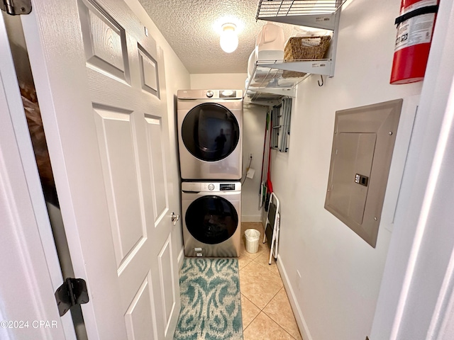 laundry room featuring a textured ceiling, stacked washer / drying machine, electric panel, and light tile patterned floors