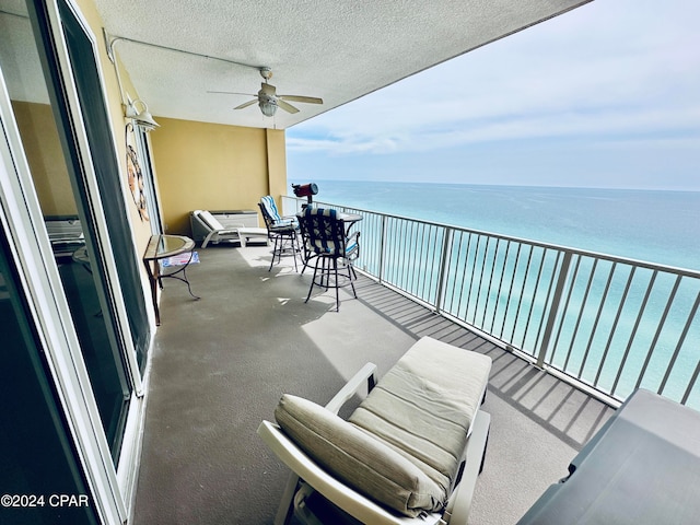 balcony featuring a water view and ceiling fan