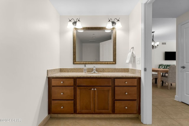 bathroom with tile patterned floors, a notable chandelier, and vanity