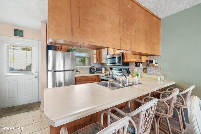 kitchen with appliances with stainless steel finishes, kitchen peninsula, a textured ceiling, and plenty of natural light