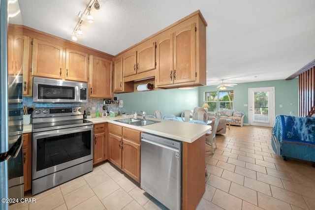 kitchen featuring kitchen peninsula, stainless steel appliances, sink, light tile patterned flooring, and tasteful backsplash