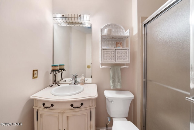 bathroom with vanity, toilet, and a shower with door