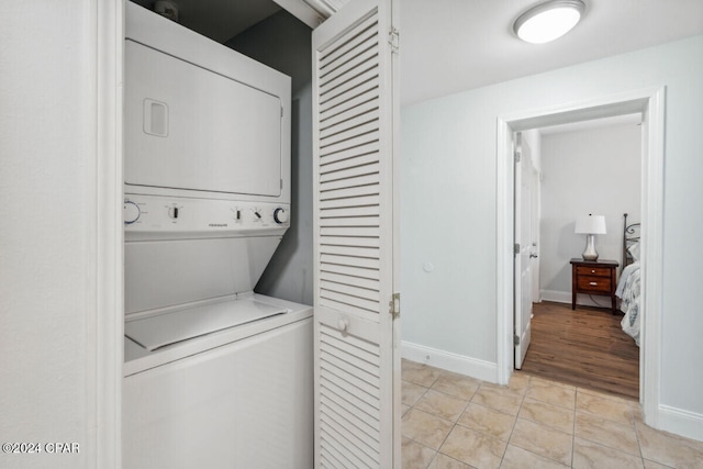 laundry area featuring stacked washer and dryer and light tile patterned floors