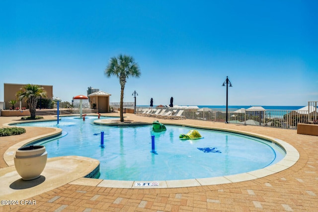 view of pool with a patio area, pool water feature, and a water view