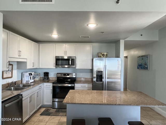 kitchen featuring light tile patterned floors, appliances with stainless steel finishes, sink, and white cabinets