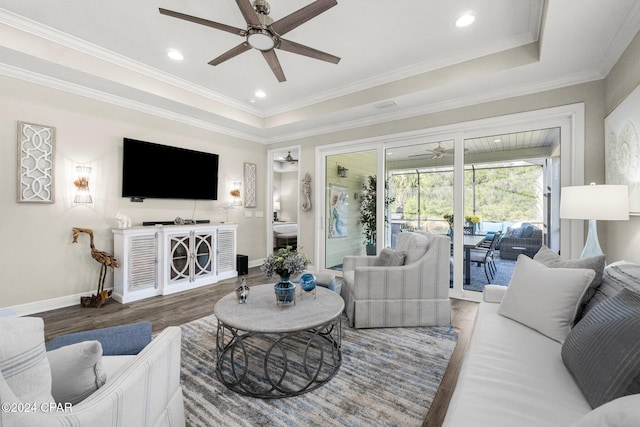 living room featuring hardwood / wood-style flooring, ceiling fan, a raised ceiling, and ornamental molding