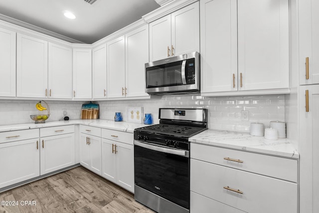 kitchen with light stone countertops, appliances with stainless steel finishes, and white cabinetry