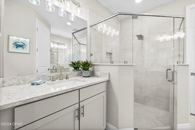 bathroom featuring a shower with door and vanity