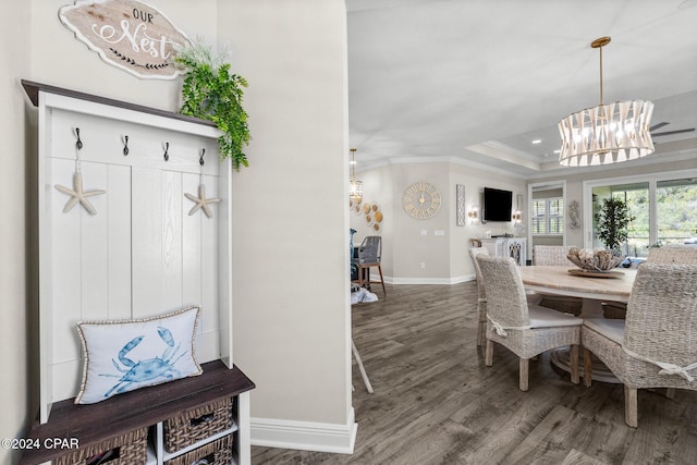 dining area with a chandelier, hardwood / wood-style flooring, a raised ceiling, and ornamental molding