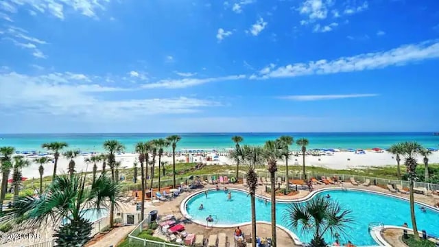 view of pool with a patio area, a water view, and a view of the beach