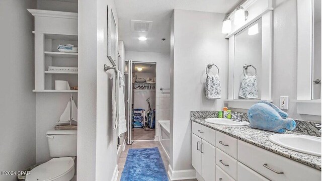 bathroom with toilet, a tub, vanity, and tile patterned flooring