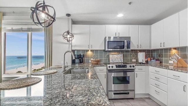 kitchen with a water view, appliances with stainless steel finishes, sink, and white cabinets