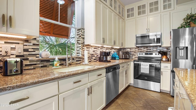 kitchen with decorative backsplash, sink, light stone counters, and appliances with stainless steel finishes