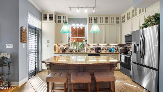 kitchen with appliances with stainless steel finishes, hanging light fixtures, light tile patterned floors, and a center island