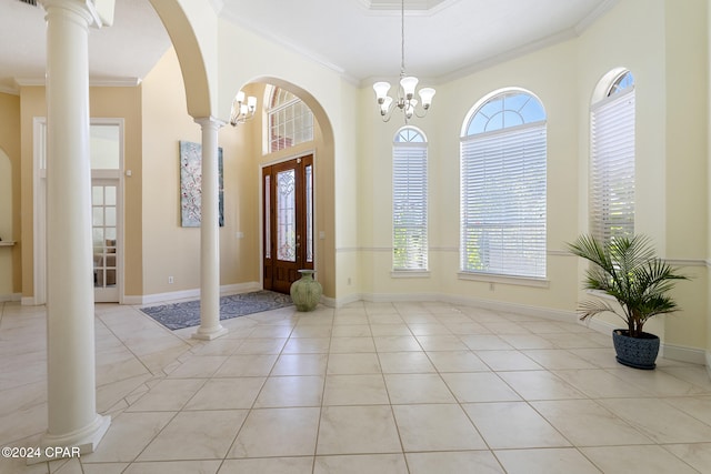 entryway with a chandelier, light tile patterned floors, ornate columns, and crown molding