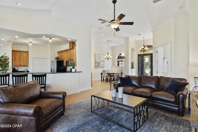 living room featuring hardwood / wood-style floors, ceiling fan with notable chandelier, and ornamental molding