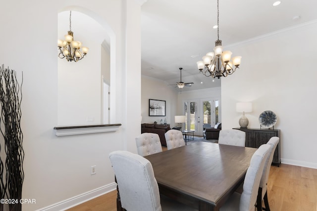 dining area featuring hardwood / wood-style floors, ceiling fan with notable chandelier, french doors, and ornamental molding