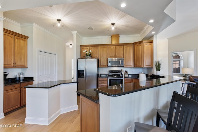 kitchen featuring dark stone counters, a center island with sink, light wood-type flooring, and appliances with stainless steel finishes