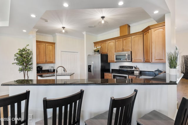 kitchen featuring a kitchen bar, kitchen peninsula, dark stone countertops, and appliances with stainless steel finishes