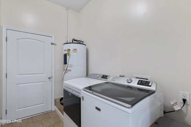 laundry area with light tile patterned flooring, electric water heater, and washing machine and clothes dryer