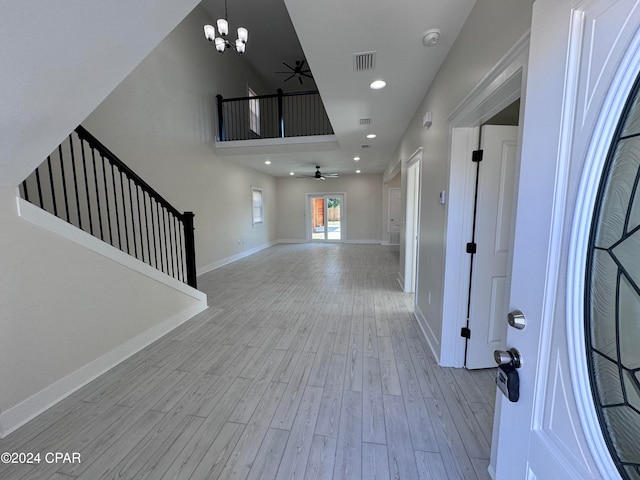 foyer featuring ceiling fan with notable chandelier and light wood-type flooring