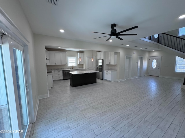 kitchen featuring stainless steel refrigerator with ice dispenser, a wealth of natural light, a kitchen island, and white cabinets