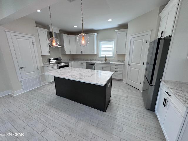 kitchen featuring white cabinetry, decorative light fixtures, stainless steel appliances, and a kitchen island